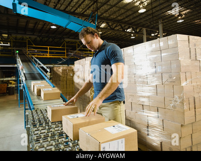 Lager Arbeiter überprüfen Pakete auf Förderband Stockfoto