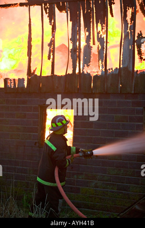 Feuerwehrmann-Angriffe totschlugen mit Feuer Schlauch Stockfoto