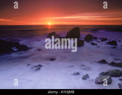 Wellen malen Felsen und Sandstrand bei Sonnenuntergang in Laguna Beach, Kalifornien Stockfoto