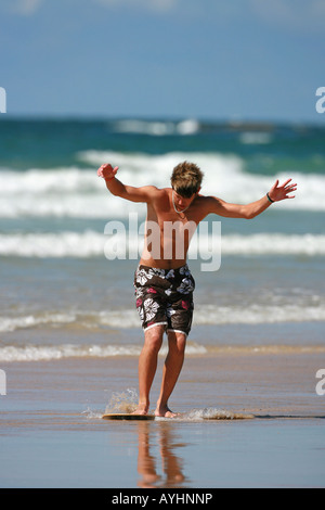 Ein junger Mann skim Boarding am Strand Stockfoto