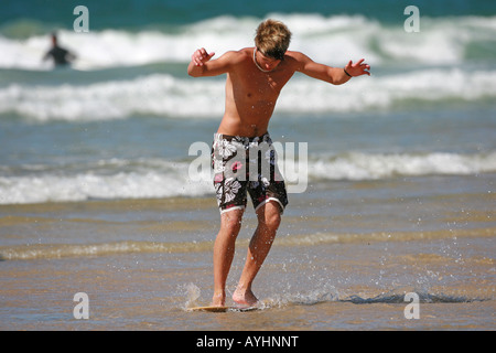 Ein junger Mann skim Boarding am Strand Stockfoto