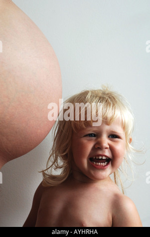 Zwei Jahre altes Mädchen Kleinkind und der Bauch der schwangeren Mutter Stockfoto