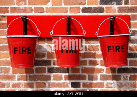 Rotes Feuer Eimer hängen vom roten Rückwand gegen eine Mauer. Stockfoto