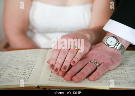 Frisch verheiratetes Paar Mann und Frau, die Hand in Hand auf standesamtliche Trauung Register Buch während der Hochzeitszeremonie UK Stockfoto