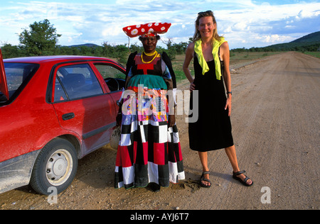 Kaokoveld eine Herero-Frau in traditioneller Kleidung, posiert für ein Foto mit einem Touristen Stockfoto