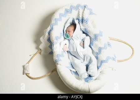 Ein Baby, das in einer Liegewanne mit Schnuller schläft. Stockfoto