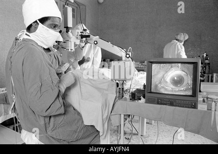 B/W eines Augenchirurgen, der eine Kataraktoperation mit Vergrößerung auf einem Monitor im Asmara-Krankenhaus durchführt. Asmara, Eritrea Stockfoto