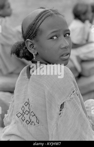 S/W eines armen jungen Mädchens mit traditionell rasierten und geflochtenen Haaren, das zurück zur Kamera blickt. Wukro, Tigray, Äthiopien, Afrcia Stockfoto