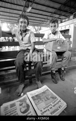 B/W von zwei Straßenjungen, die Zeitungen und Zigaretten an einem Busbahnhof in San Pedro Sula verkaufen. Honduras Stockfoto