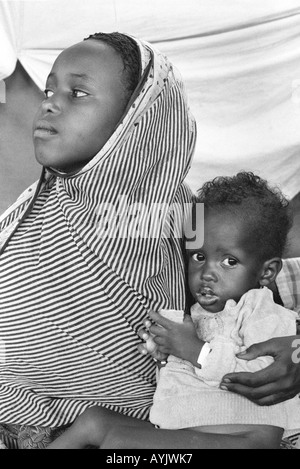 S/W-Porträt eines jungen somalischen Flüchtlingsmädchens mit einem unterernährten Kind in einem Notversorgungs-Zentrum an der Grenze zu Somalia. Kebrebeyah, Äthiopien Stockfoto
