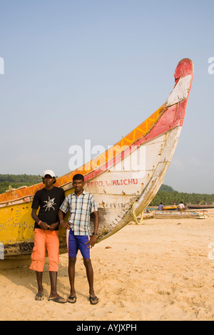 Zwei jungen stehen neben einem Angeln Boot auf Chowara Strand, Chowara, Kovalam, Kerala, Indien Stockfoto