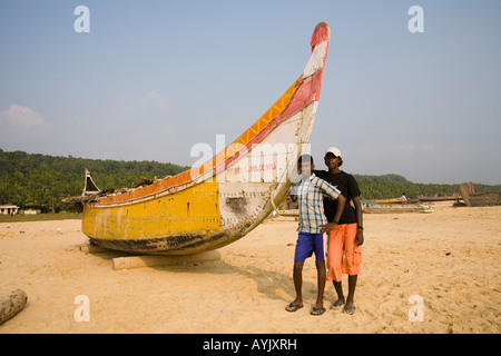 Zwei jungen stehen neben einem Angeln Boot auf Chowara Strand, Chowara, Kovalam, Kerala, Indien Stockfoto