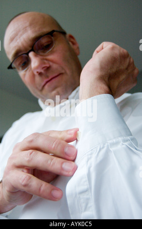 Glatze Mann mit Brille ist die Taste auf seinem Hemdsärmel schließen. Stockfoto
