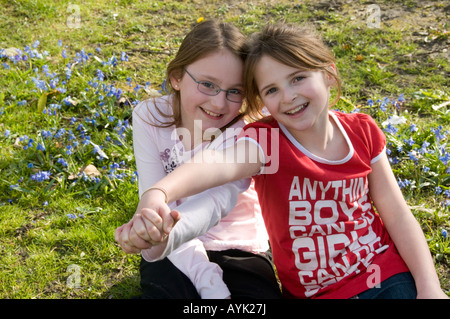 Zwei glücklich lächelnd neun Jahre alten Freundinnen spielen zusammen Arm in Arm in der lokalen park Aberystwyth Wales UK Stockfoto