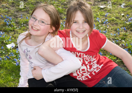 Zwei glücklich lächelnd neun Jahre alten Freundinnen spielen zusammen Arm in Arm in der lokalen park Aberystwyth Wales UK Stockfoto