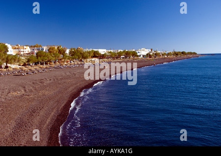 Die schwarzen Sandstrände mit Sonnenschirmen und Liegestühlen in Kamari auf der griechischen Insel Santorini Griechenland Stockfoto