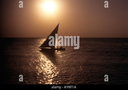 Dhau unter Segel bei Sonnenuntergang an der Küste in Stone Town, Sansibar, Tansania Stockfoto