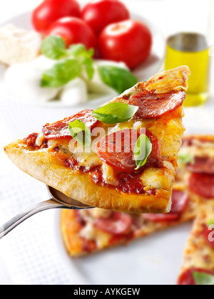 Pizzastück mit Peperoni gekrönt. Stockfoto