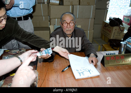 Herr Yang Peiyan, einer der Bauern, die Terrakottasoldaten im Jahr 1974 posieren für ein Foto und Unterschrift Bücher entdeckt Stockfoto