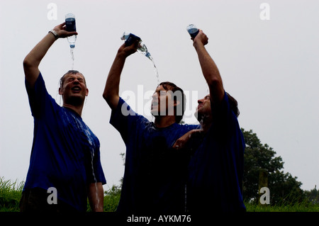 Läufer, die Abkühlung durch strömenden Wasser über ihren Köpfen Stockfoto