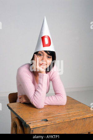 ziemlich Erwachsener Schüler in einem Klassenzimmer mit einem Dummköpfe Mütze glum suchen Stockfoto
