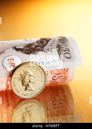 Eine stehende Münze neben gerollt Pfund Sterling Hinweis Stockfoto