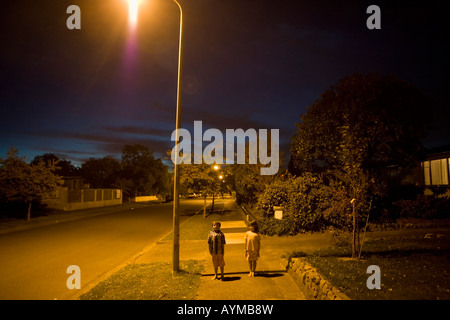 Bruder im Alter von sechs und Schwester im Alter von vier Stand unter Straßenlaterne auf einer öffentlichen Straße in Palmerston North New Zealand Stockfoto