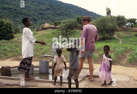 Dorfbewohner, der einem Westler erklärt, wie man die Wasserpumpe im Dorf Chembe, Cape Maclear, Malawi-See, Malawi, benutzt. Afrika Stockfoto