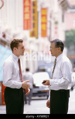 Asiatische und westliche Geschäftsleute sprechen in der Straße Stockfoto