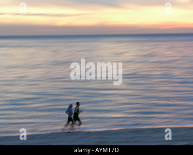 Paar am Strand bei Sonnenuntergang Bewegungsunschärfe Beine laufen Stockfoto