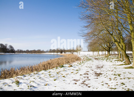 Einen schneebedeckten Pfad am See in Blickling im ländlichen England Norfolk im zeitigen Frühjahr Stockfoto