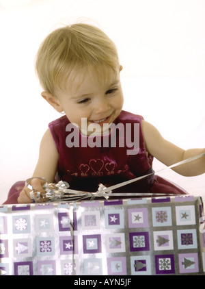 Lächelndes Babymädchen öffnen ein Weihnachtsgeschenk Stockfoto