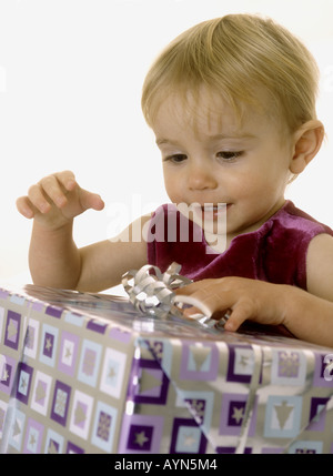 Lächelndes Babymädchen öffnen ihr Weihnachtsgeschenk Stockfoto