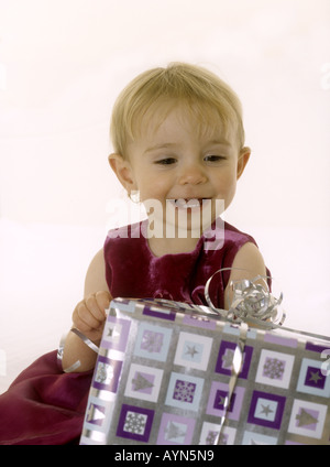 Lächelndes Babymädchen Blick auf ein Weihnachtsgeschenk Stockfoto