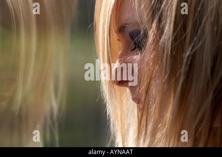 Junge blonde junge Frau weinen vor schmutzigen Fenster mit Reflexion zur Veranschaulichung von Student psychische Gesundheit Stockfoto