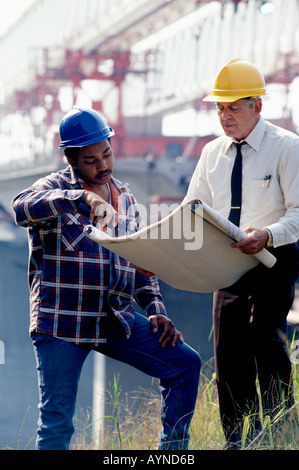 Kaukasische Architekt afroamerikanische Vorarbeiter Überprüfung Blaupausen auf Baustelle Stockfoto