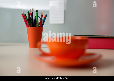 Tasse Kaffee neben einer Tasse mit Bleistiften Stockfoto