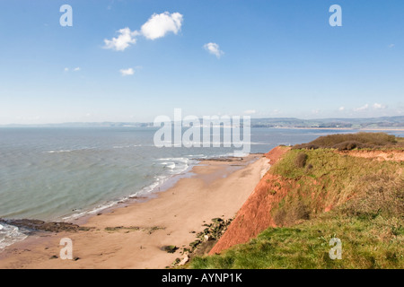 Rote Klippen sandigen Strand und Blick über die Mündung des Fluss Exe in Richtung der dunstigen fernen Hügel von Dartmoor Stockfoto