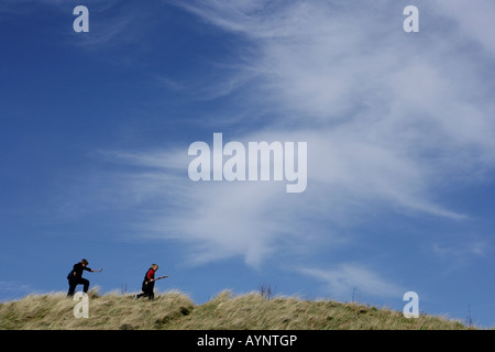 Zwei junge Burschen, die entlang einer grasbewachsenen Bank mit einem blauen Himmel im Hintergrund. Stockfoto