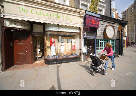 Frau mit Kinderwagen vorbei Chelsea Oxfam Shop Welten Ende London SW3 Stockfoto