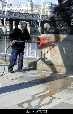 Männliche Arbeiter verwendet einen Hochdruckreiniger, Graffiti von der Wand auf dem Londoner Themse-Ufer zu entfernen Stockfoto