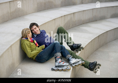 Junges Paar Inline-Skates sitzt auf einer Treppe tragen Stockfoto