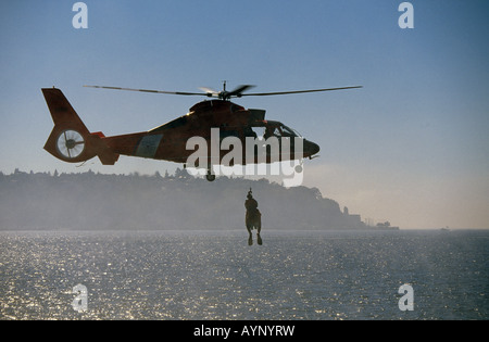 Vereinigte Staaten Küstenwache Hubschrauber wirft ein Rettungsschwimmer und ein Schiffswrack Opfer aus einem umgedrehten Boot im Hafen von Seattle. Stockfoto