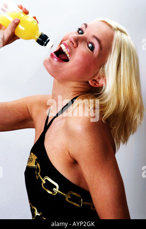 Blonde Frau trinken aus einer Saftflasche | Blonde Lachende Frau Drinkt aus Einer Saftflasche Stockfoto