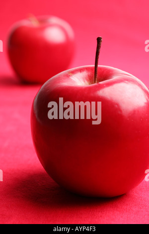 Zwei rote glänzende Äpfel auf rotem Grund Stockfoto