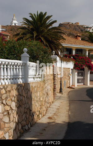 Das Coastial Resort beherbergt Andalusien Spanien mit Steinmauern, weißen Balustraden, Palmen und einer fernen weißen Stupa unter klarem Himmel. Stockfoto
