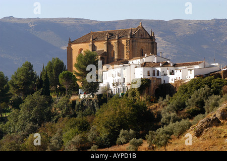 Malerischer Blick auf Ronda, Andalusien, Spanien, mit historischen weißen Häusern und einer großen Kirche auf einem Hügel vor Bergkulisse. Stockfoto