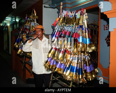 Lokaler Mann verkaufen hell farbigen Papier Trompeten für Neujahrsfeiern, Kuta, Bali, Indonesien. Stockfoto