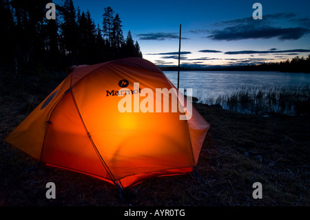 Zelt von innen beleuchtet, in der Dämmerung auf einem See, Femundsmark, Norwegen Stockfoto