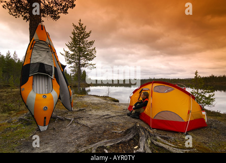 Zwei aufblasbare Kajaks und eine Frau sitzen vor einem Zelt am See, Femundsmarka Nationalpark, Femundsmark, Norwegen Stockfoto